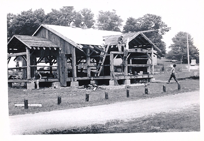 black and white view of the construction of the Ingersoll cheese museum, with two men on the roof